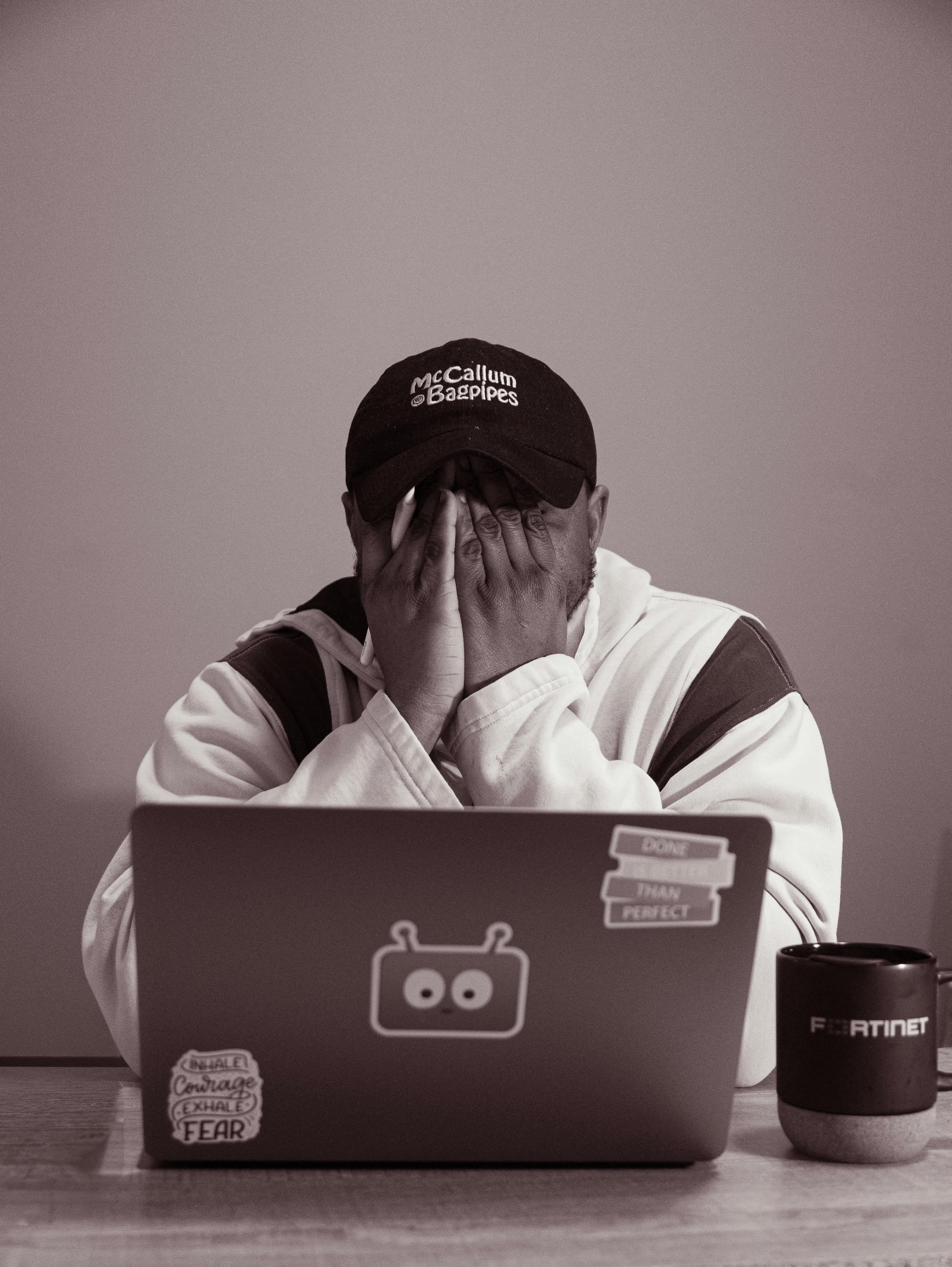 A person sitting at a laptop with their head in their hands